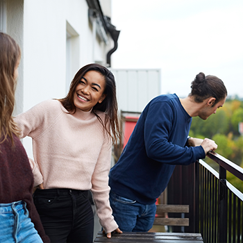 tre personer som står ute på en balkong
